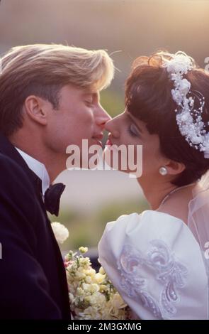Ein junges frisch verheiratetes Paar küsst sich auf der Hochzeit Stockfoto