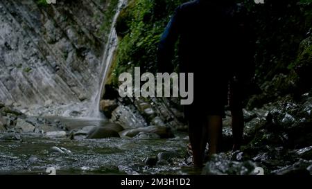 Ein Spaziergang auf den Felsen mit einem sprudelnden Bach. Kreativ. Kleine Wasserfälle mit kaltem Wasser, wo Touristen schwimmen und spazieren gehen. Hochwertige 4K-Aufnahmen Stockfoto