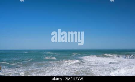 Stürmendes Meer. Aktion . Blaues, transparentes Wasser, das von Wellen an die Küste vor dem Hintergrund eines blauen wolkenlosen Himmels geworfen wird. 4 von hoher Qualität Stockfoto