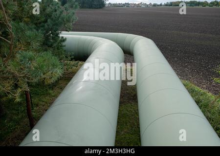 Infrastruktur für den Transfer von Wärmeenergie. Zentralheizungsrohre in einem thermischen Schutzmantel aus Metall, der in europa über dem Boden verlegt ist. Stockfoto