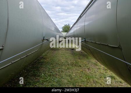 Infrastruktur für den Transfer von Wärmeenergie. Zentralheizungsrohre in einem thermischen Schutzmantel aus Metall, der in europa über dem Boden verlegt ist. Stockfoto