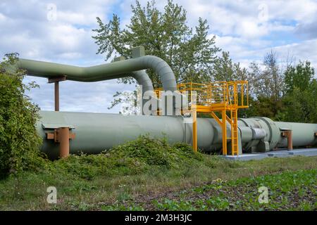 Infrastruktur für den Transfer von Wärmeenergie. Zentralheizungsrohre in einem thermischen Schutzmantel aus Metall, der in europa über dem Boden verlegt ist. Stockfoto