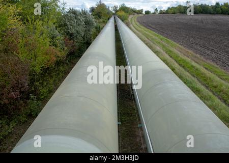 Infrastruktur für den Transfer von Wärmeenergie. Zentralheizungsrohre in einem thermischen Schutzmantel aus Metall, der in europa über dem Boden verlegt ist. Stockfoto