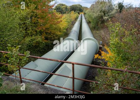 Infrastruktur für den Transfer von Wärmeenergie. Zentralheizungsrohre in einem thermischen Schutzmantel aus Metall, der in europa über dem Boden verlegt ist. Stockfoto