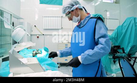 Arztpraxis. Kreativ . Ein wunderschöner, geräumiger Raum, in dem Sie einen Mann in Uniform mit Brille bei der Arbeit sehen können, der Operationen durchführt und Medizin bewegt Stockfoto