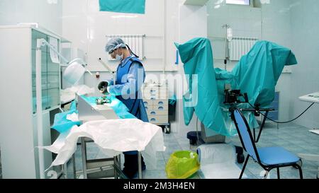 Arztpraxis. Kreativ . Ein wunderschöner, geräumiger Raum, in dem Sie einen Mann in Uniform mit Brille bei der Arbeit sehen können, der Operationen durchführt und Medizin bewegt Stockfoto