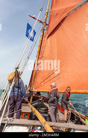 Besatzung, die an Bord des traditionellen Gaff Cutters „Jolie Brise“ arbeitet und im Wind in Solent, Hampshire, Großbritannien, läuft Stockfoto