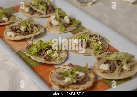 Nahaufnahme von Chalupas, typisches mexikanisches Gericht mit Tortillas, Sauce, Käse, Fleisch und Salat. Stockfoto