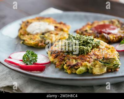 Hausgemachte vegane Zucchini-Pommes mit drei Saucen. Stockfoto