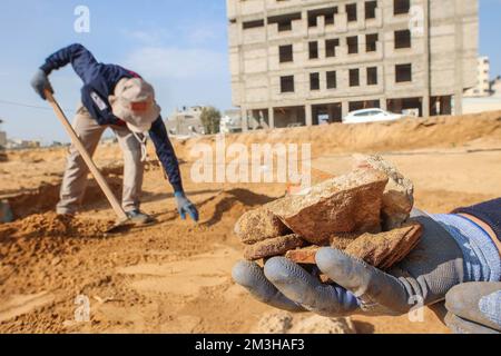 Gaza, Palästina. 15.. Dezember 2022. Ein palästinensischer Arbeiter trägt Artefakte von Keramik, die auf einem neu entdeckten Friedhof aus der Römerzeit im Gazastreifen gefunden wurden. Die Hamas-Behörden in Gaza gaben die Entdeckung von über 60 Gräbern in der alten Grabstätte bekannt. Seit der Entdeckung des Geländes im Januar letzten Jahres während der Vorbereitungen für ein von Ägypten finanziertes Wohnungsbauprojekt wurden die Baustellen von Arbeitskräften ausgehoben. (Kreditbild: © Ahmed Zakot/SOPA Bilder über ZUMA Press Wire) Stockfoto