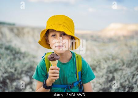Tourismusjunge, der türkisches Eis isst, während er das Tal mit Felsformationen und Feenhöhlen in der Nähe von Goreme in Kappadokien, Türkei, erkundet Stockfoto