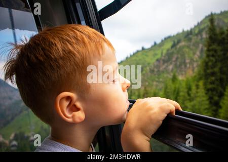 Der Junge schaut von der Hütte aus auf die Berge Stockfoto