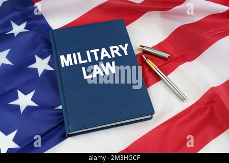 Regelkonzept. Auf der US-Flagge liegt ein Stift und ein Buch mit der Inschrift - MILITÄRRECHT Stockfoto