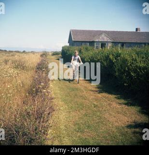 1960er, historisch, ein Junge, der mit seinem Fahrrad der Epoche, einem Herkules-Jeep, auf einem grasbedeckten Pfad neben einer Wiese an der Küste, England, Großbritannien, der junge Mann, Tragen ein kurzärmeliges gestreiftes Oberteil und Shorts. Befindet sich auf einem in Großbritannien hergestellten Mini-Roadster, hergestellt von der Hercules Cycle & Motor Cycle Company. Ein britisches Unternehmen, das 1910 in Aston, Birmingham, England, gegründet wurde, Ende der 1930er Jahre war das Unternehmen zum größten Fahrradhersteller der Welt geworden. Stockfoto