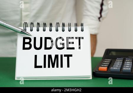 Geschäftskonzept. Auf einer grünen Oberfläche befindet sich ein Taschenrechner, ein Mann zeigt mit einem Stift auf ein Notizbuch mit der Aufschrift - Budget Limit Stockfoto