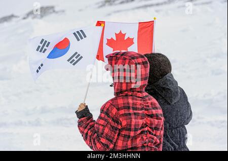 Zwei Touristen mit japanischer und kanadischer Flagge auf einem Winterberg in Kanada Stockfoto