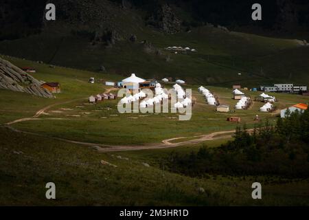 Jurtencamp umgeben von Bäumen auf dem Bergrücken. An einem sonnigen Tag auf dem Hügelkamm kleine Ger-Hütten. Stockfoto