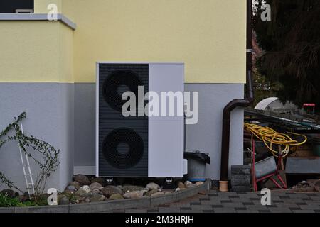 Dunkelgraue, außerhalb des Hauses installierte Wärmepumpe mit grauem und pastellgelbem Anstrich für Heiz- und Kühlzwecke. Stockfoto