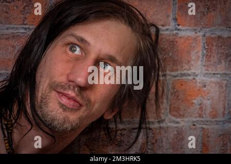 Behaarter roter Mann in der Nähe der alten orangefarbenen Mauer Stockfoto