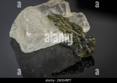 Moldavitstein und weißer großer Stein auf glänzendem schwarzem dunklem Tisch Stockfoto