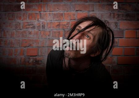 Behaarter Mann mit grüner Mütze und zehn Marihuana-Joints in der Nähe von alten roten Ziegelmauern Stockfoto