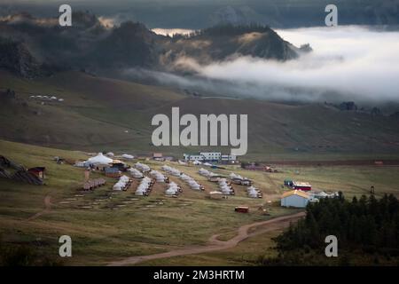 Winzige Häuser, umgeben von Bäumen auf dem Bergrücken. An einem sonnigen Tag auf dem Hügelkamm kleine Ger-Hütten. Stockfoto