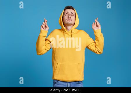 Junger Mann in gelbem Sweatshirt mit gedrückter Fingerbewegung Stockfoto