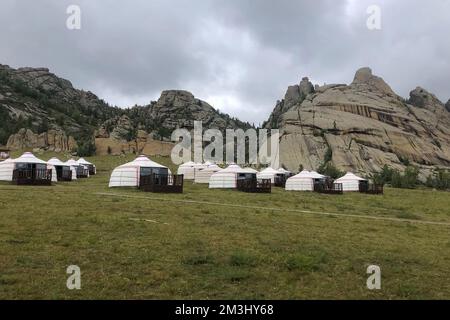 Jurtencamp umgeben von Bäumen auf dem Bergrücken. An einem bewölkten Tag gibt es auf dem Hügelkamm kleine Bierhütten. Stockfoto