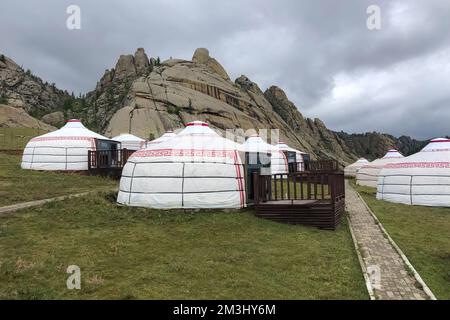 Jurtencamp umgeben von Bäumen auf dem Bergrücken. An einem bewölkten Tag gibt es auf dem Hügelkamm kleine Bierhütten. Stockfoto