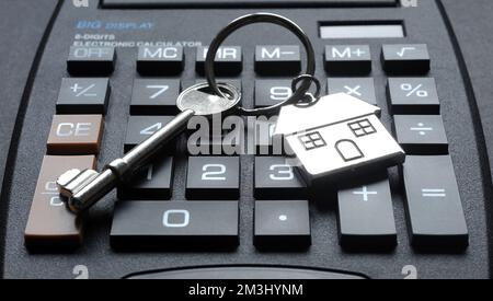 HAUSSCHLÜSSEL UND SCHLÜSSELANHÄNGER MIT TASCHENRECHNER RE HYPOTHEKENZAHLUNGEN WOHNUNGSMARKT LEBENSKOSTENKRISE ETC. UK Stockfoto