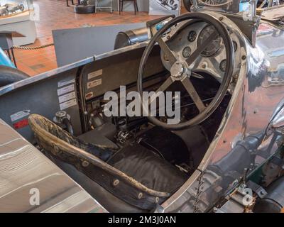 Der Fahrer fährt das Cockpit eines 1933 gebauten Rennwagens mit Napier-Railton-Aeromotive, das von Reid Railton im Brooklands Museum, Surrey, Großbritannien, entworfen wurde. Stockfoto