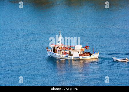Ein traditionelles hölzernes Fischerboot, das auf dem farbenfrohen Wasser schwimmt, Ermioni, Griechenland. Stockfoto