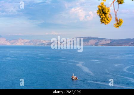 Ein traditionelles hölzernes Fischerboot, das auf dem farbenfrohen Wasser schwimmt, Ermioni, Griechenland. Stockfoto