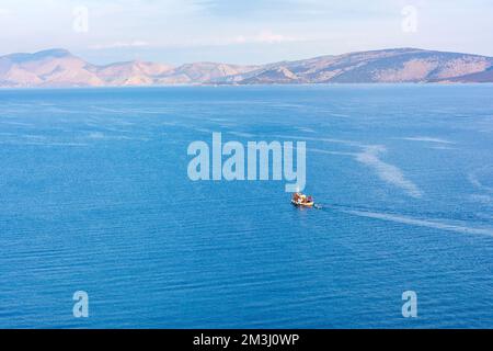 Ein traditionelles hölzernes Fischerboot, das auf dem farbenfrohen Wasser schwimmt, Ermioni, Griechenland. Stockfoto