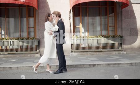 Liebevolles Hochzeitspaar auf der Straße der Stadt. Junger Bräutigam und Braut im Freien, Konzept von Liebe und Fürsorge Stockfoto
