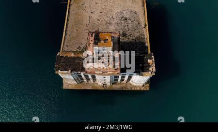 Luftaufnahme auf einen alten rostigen Pier und blaues türkisfarbenes Wasser. Schuss. Verlassener alter Betonpier und das Meerwasser Stockfoto