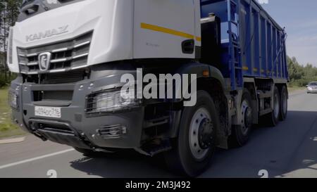 Ein riesiger blauer Truck. Szene: Ein Lkw mit blauer Karosserie, der langsam entlang der Autobahn fährt, befindet sich neben einem grünen Wald. Hochwertige FullHD-Aufnahmen Stockfoto