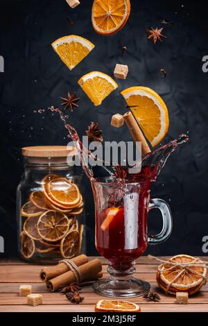 Glühwein Glühweine Glühweinzutaten, Zitrusfrüchte, Zimt und Sternanis fliegen aus der Höhe und sorgen für Spritzer. Ein Glas Glühwein auf einem Stockfoto