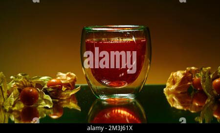 Stillleben mit Cognac. Stock Clip. Orangefarbener Hintergrund mit Blick auf ein alkoholisches kohlensäurehaltiges Getränk und kleine Tangerinen in der Nähe. Hohe Qualität 4K f Stockfoto