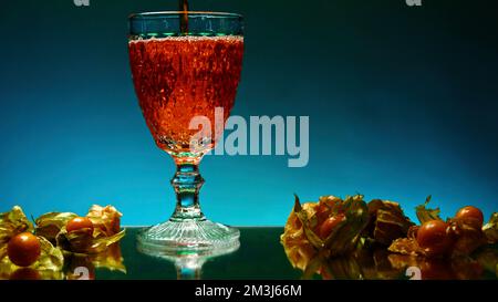Wunderschöner beleuchteter Hintergrund. Stock Clip. Wunderschöne, geräumige Gläser mit einem alkoholischen Getränk mit Gasen auf dem Hintergrund von Tangerinen und Orangen. H Stockfoto