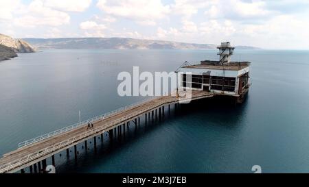 Luftaufnahme auf einen alten rostigen Pier und blaues türkisfarbenes Wasser. Schuss. Verlassener alter Betonpier und das Meerwasser Stockfoto