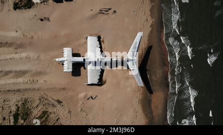 Ein militärisches Geheimflugzeug am Ufer des Meeres. Aktion. Luftaufnahme eines verlassenen Flugzeugs an einem Sandstrand Stockfoto