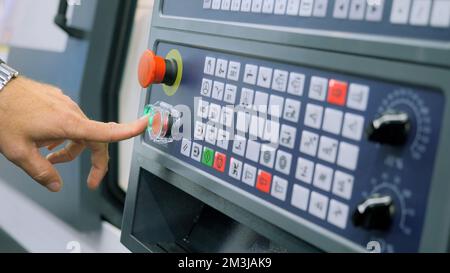 Mitarbeiter arbeitet im Werk hinter dem Bedienfeld der Produktionsmaschine. Medien. Industrieproduktion, Schwermaschinen Stockfoto