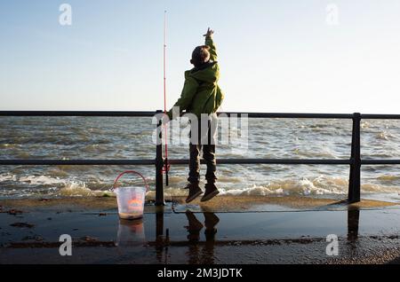 Junge, die am Kai am Meer nach Krabben fischen Stockfoto