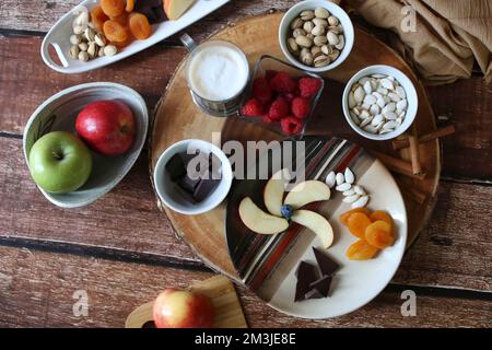 Flache Aufnahme von Wurstplatte mit Früchten und Nüssen, brauner Hintergrund Stockfoto