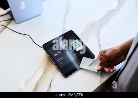 Hand einer weiblichen Kundin, die über das POS-System im Café bezahlt Stockfoto