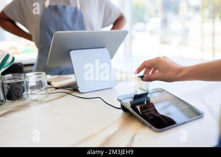 Gekürzte Hand auf Frau, die eine Kreditkarte in ein modernes POS-System einsteckt Stockfoto