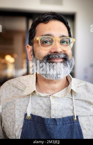 Porträt eines lächelnden Caféladenbesitzers mit Bart und Brille Stockfoto