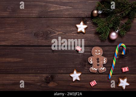 Weihnachtskomposition mit Lebkeksen, Tannenzweigen und weihnachtsdekor auf Holztisch mit Platz für Text. Stockfoto