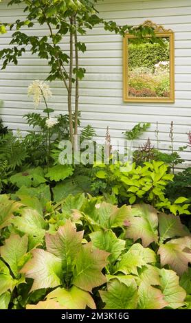 Gerahmter Spiegel an der Seitenwand des Schuppens im Garten im Garten im Sommer. Stockfoto